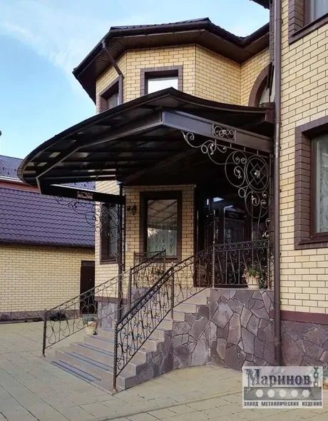 Кованый орнамент металлического навеса у входа в частный дом